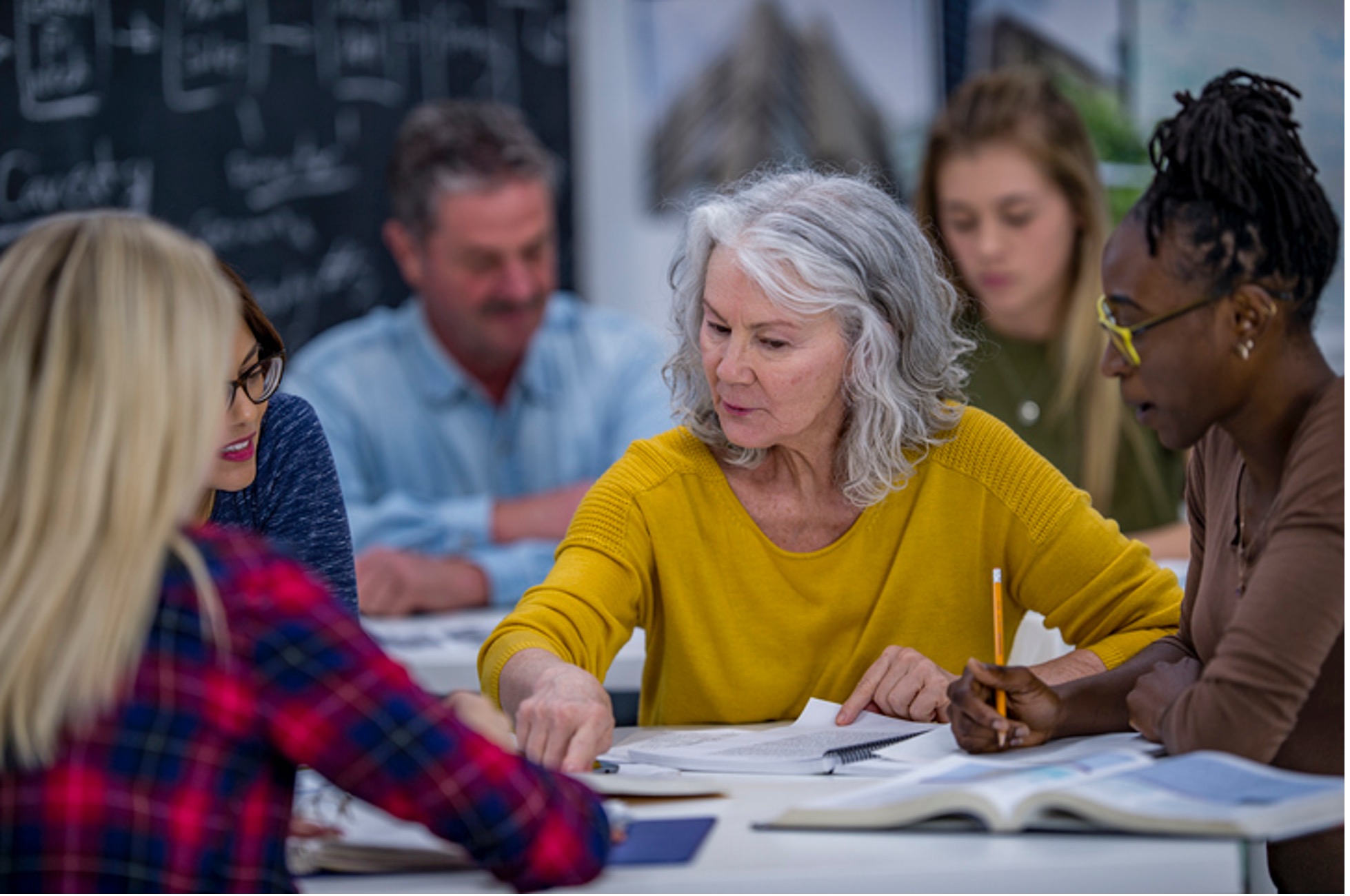 Senior student and younger students working together in a college setting.