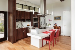 Ahighceilingedfully-functionalkitchenwithapplianceskitchenislandwithhobandplacematsandseatingontheislandfortwopeople